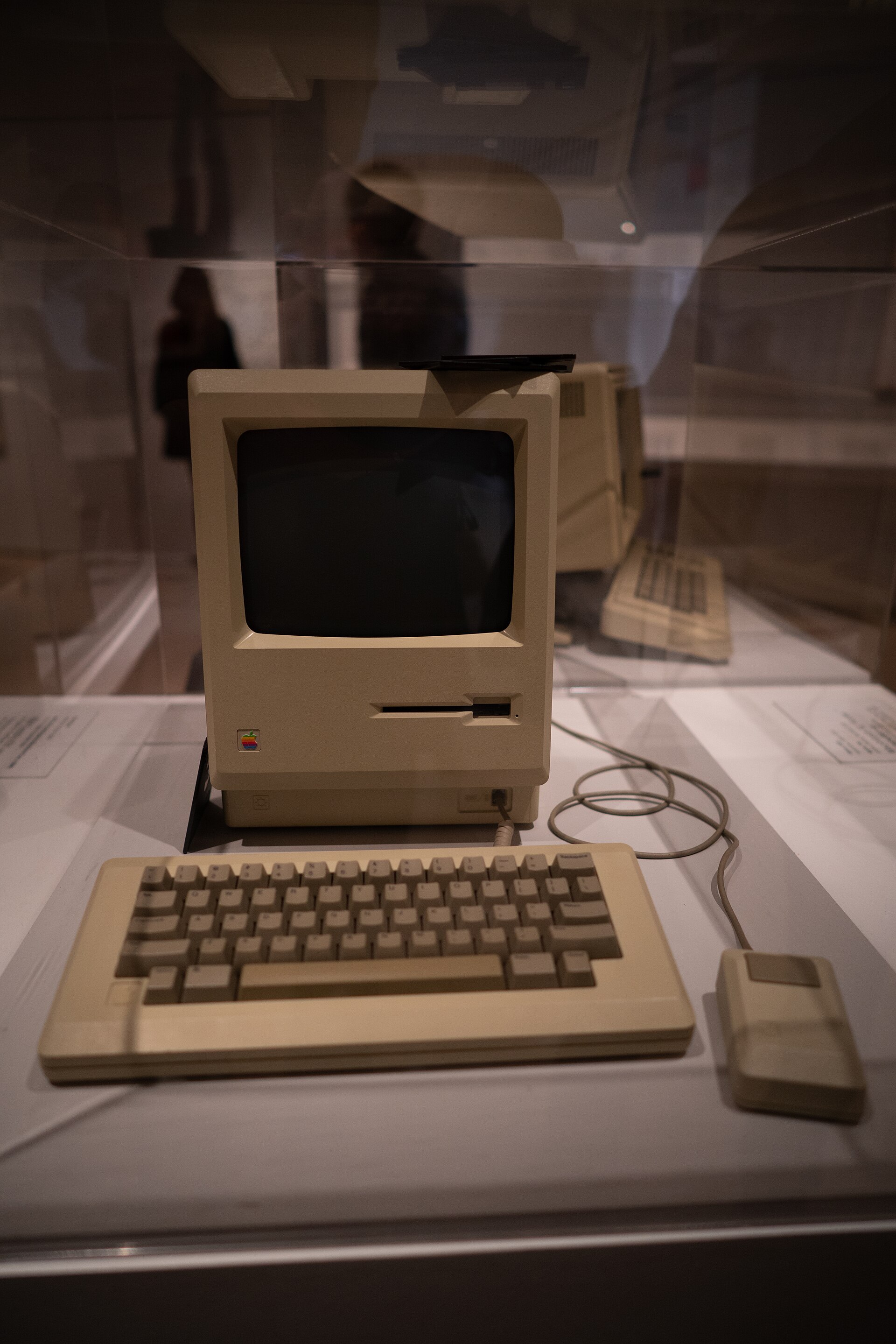 An original Apple Macintosh 128K computer, keyboard and mouse displayed in a glass case in MoMA's design galleries
