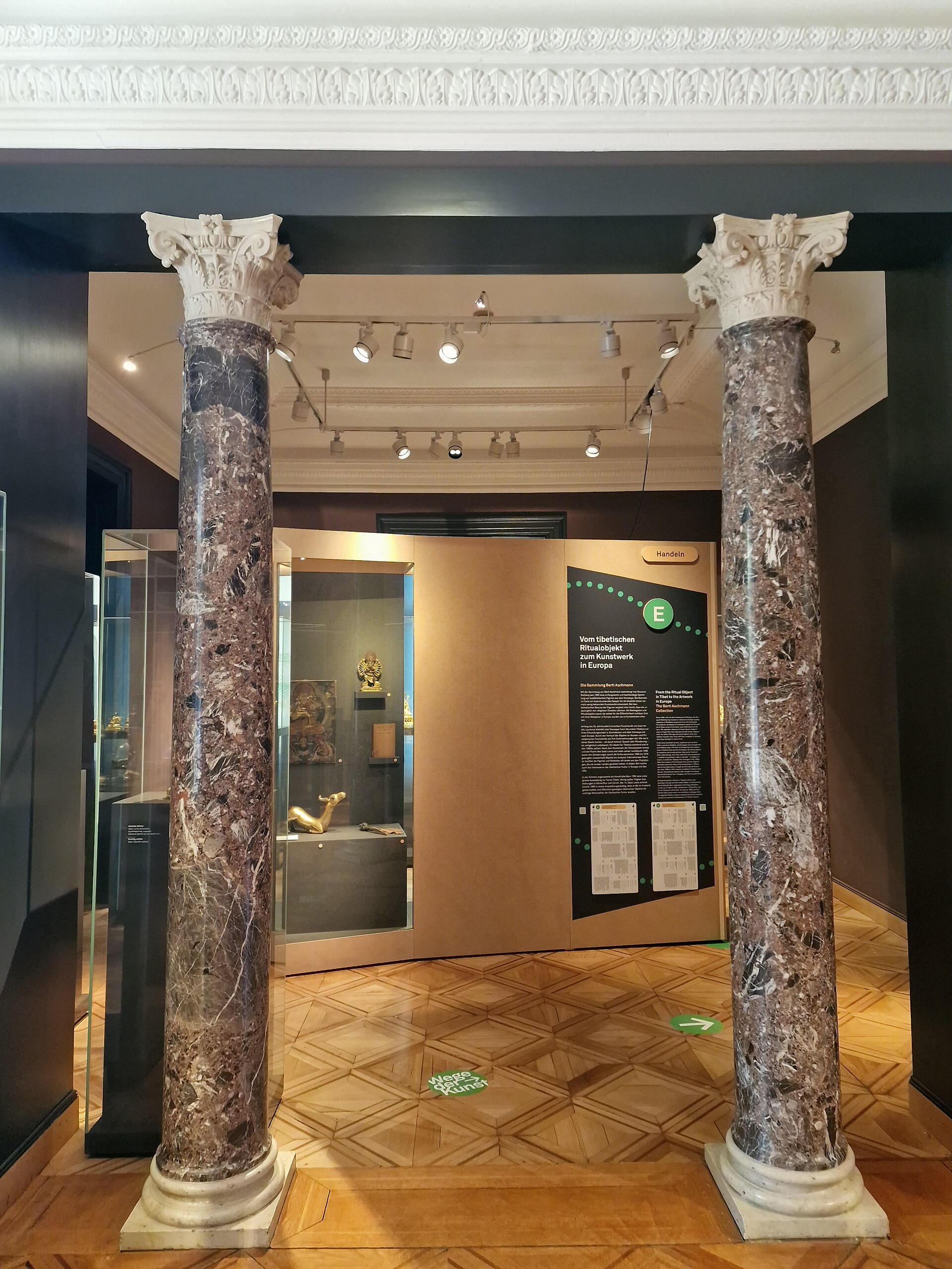 Gallery display in the Himalayas department, with a didactic panel on Tibetan sacred objects entering European collections and vitrines of Buddhist art