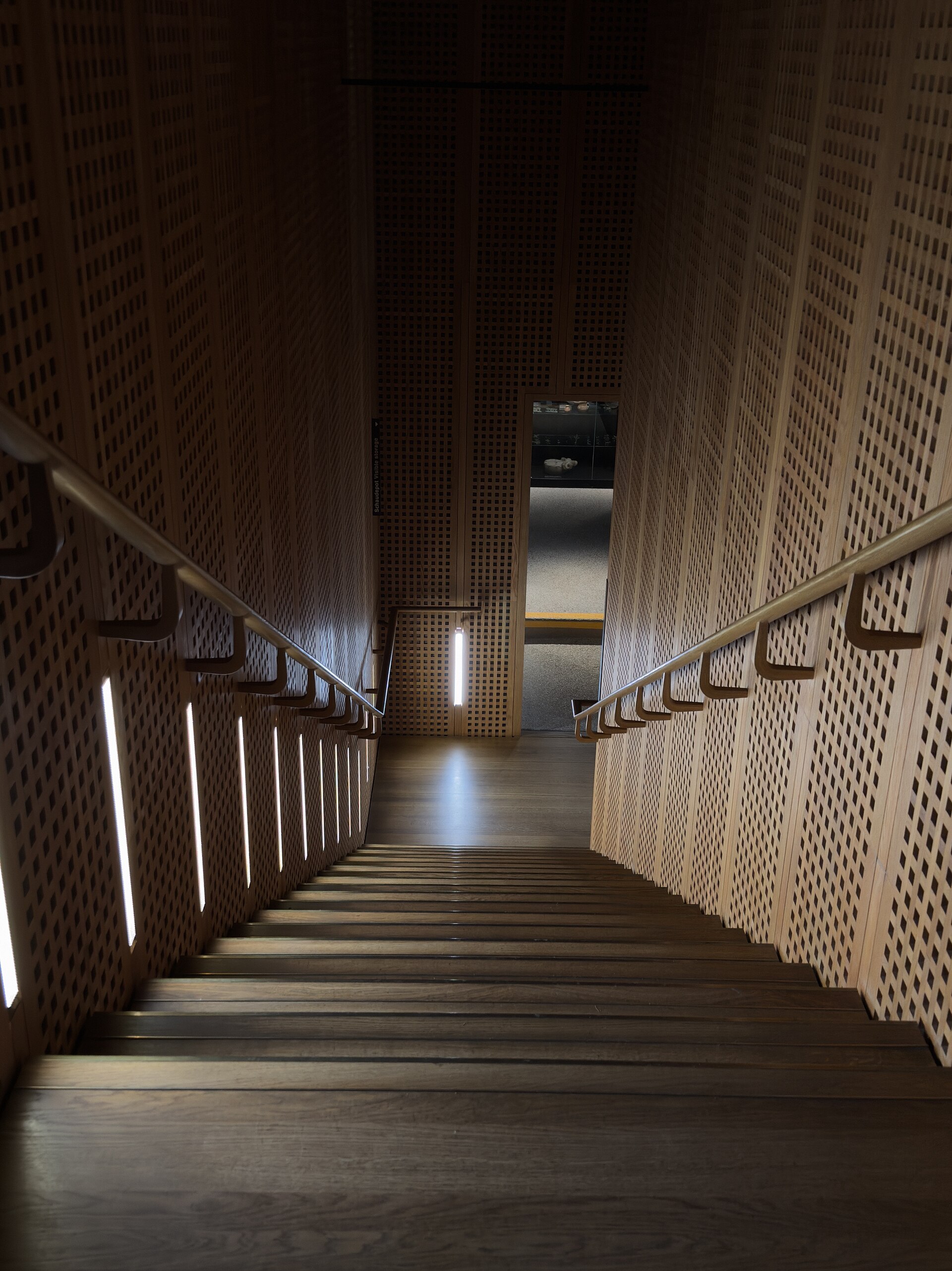 Interior staircase in the Smaragd extension, clad in perforated wooden panels with integrated LED lighting