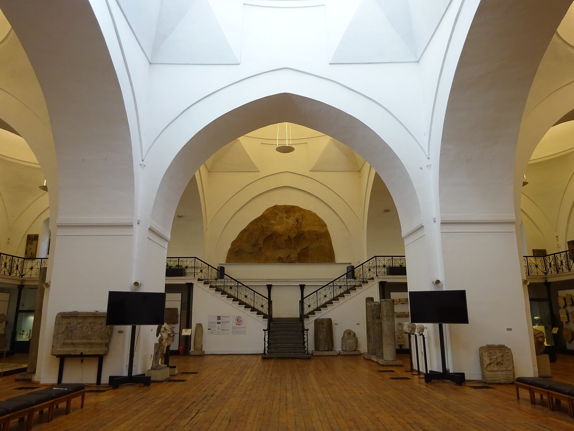 View toward the central staircase and mezzanine gallery, with the plaster cast of the Madara Horseman set in the arch above the landing