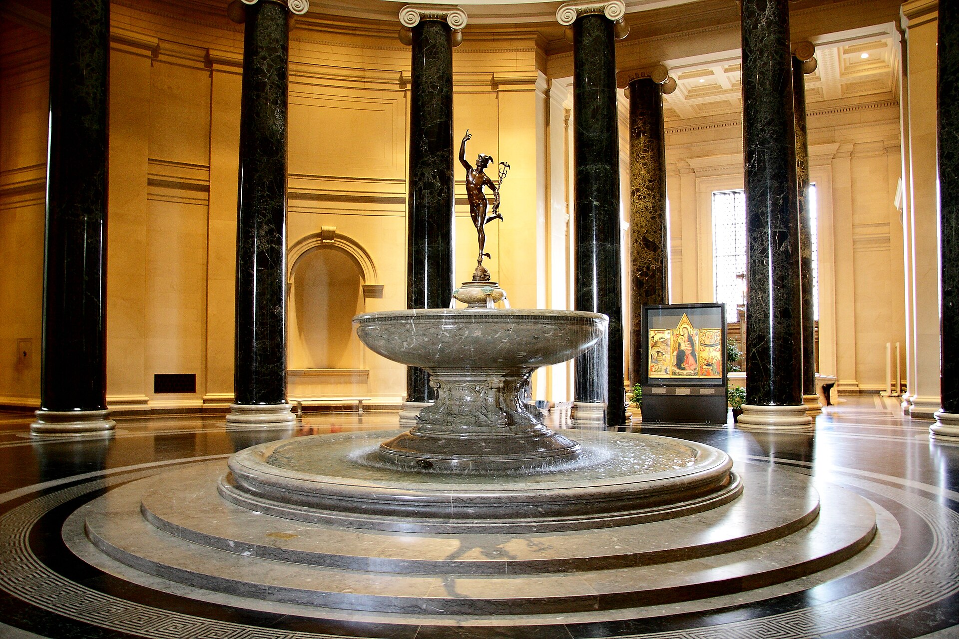 The West Building Rotunda, ringed with black marble Ionic columns, with the bronze Mercury fountain at its center