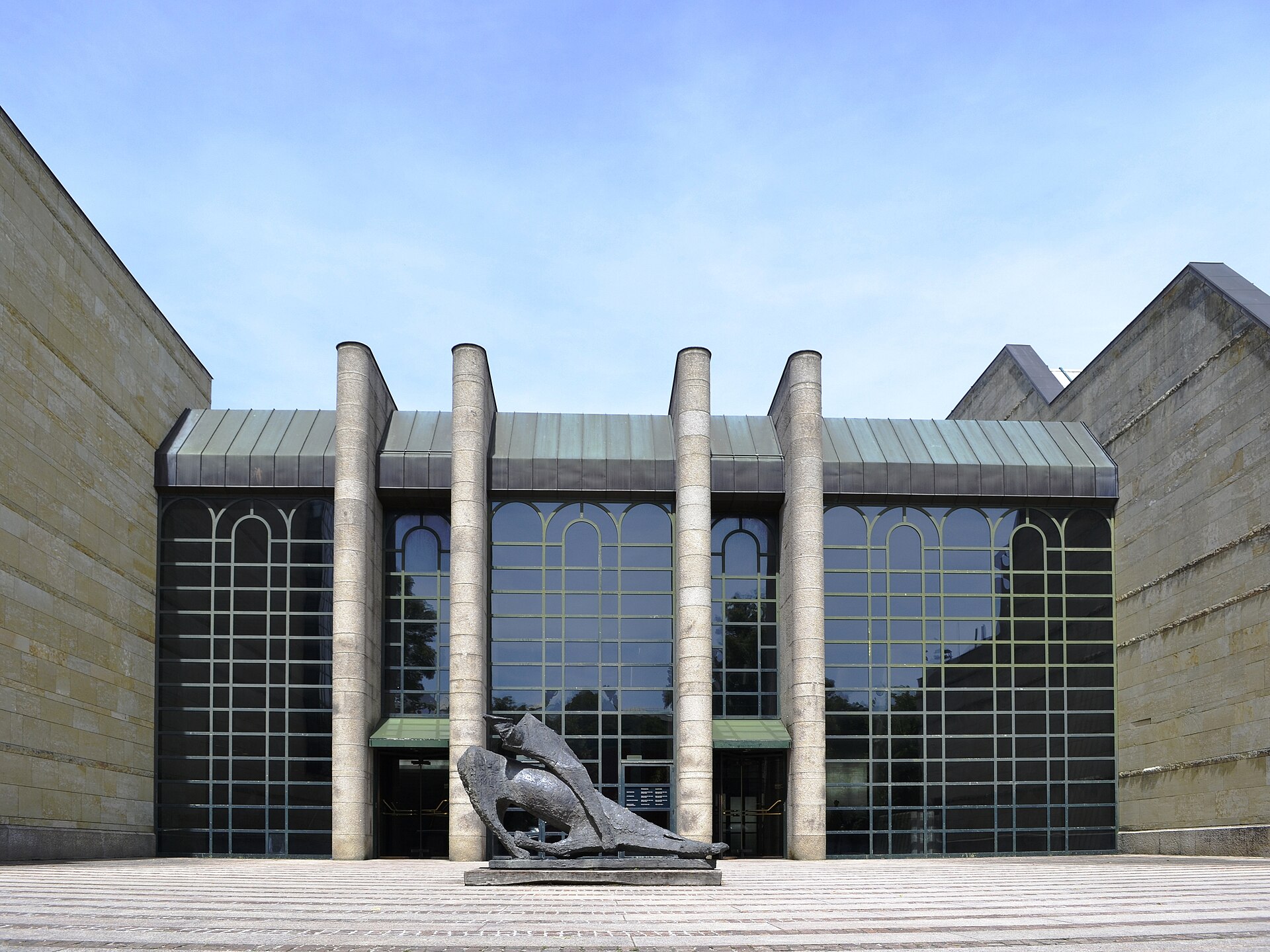 The postmodern entrance front, stone-faced columns and a stepped stone stair leading up to the glazed entrance bays