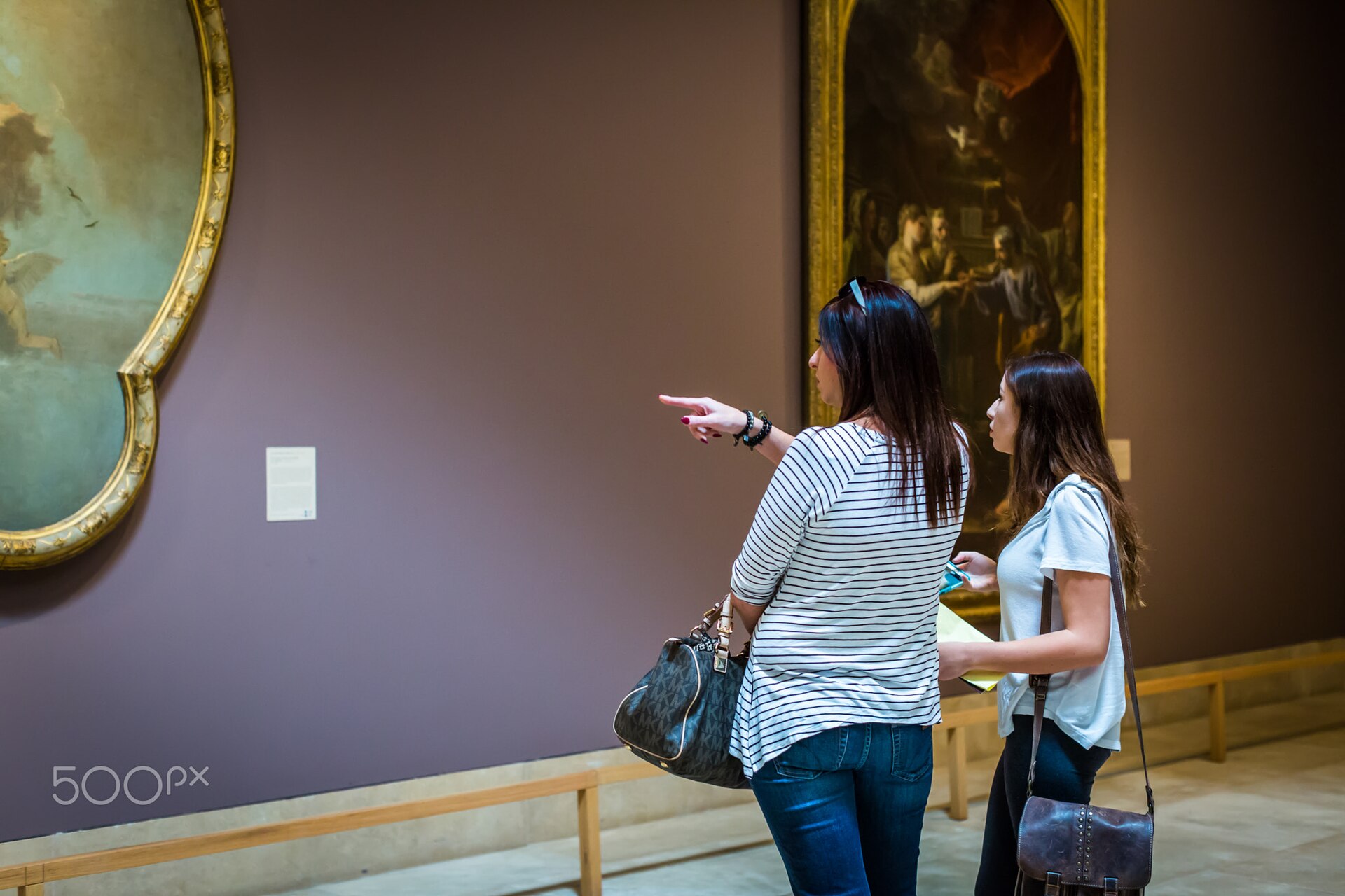Visitors in a gallery of gilt-framed European Old Master paintings