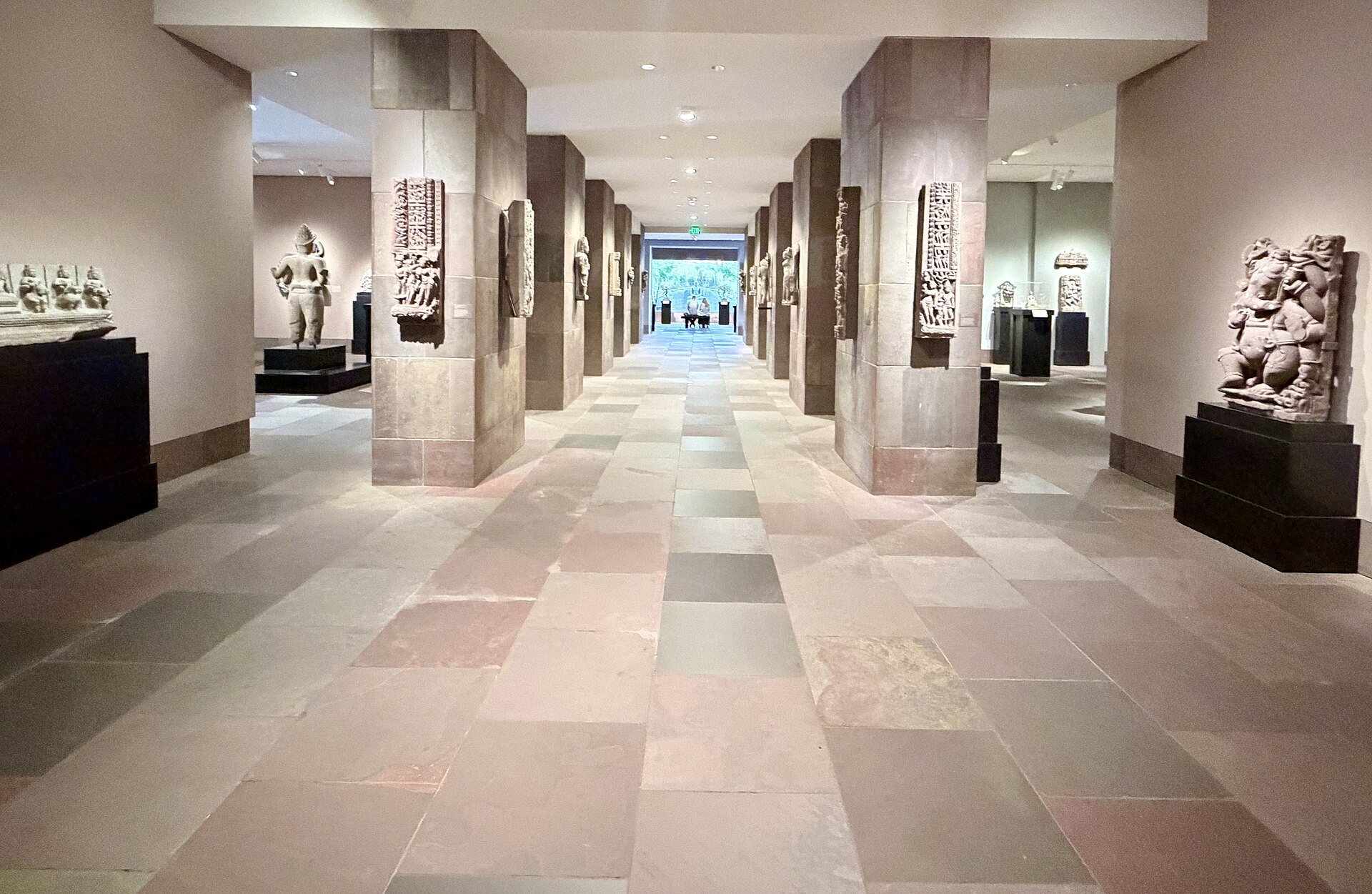 A gallery corridor of South and Southeast Asian stone sculpture on plinths