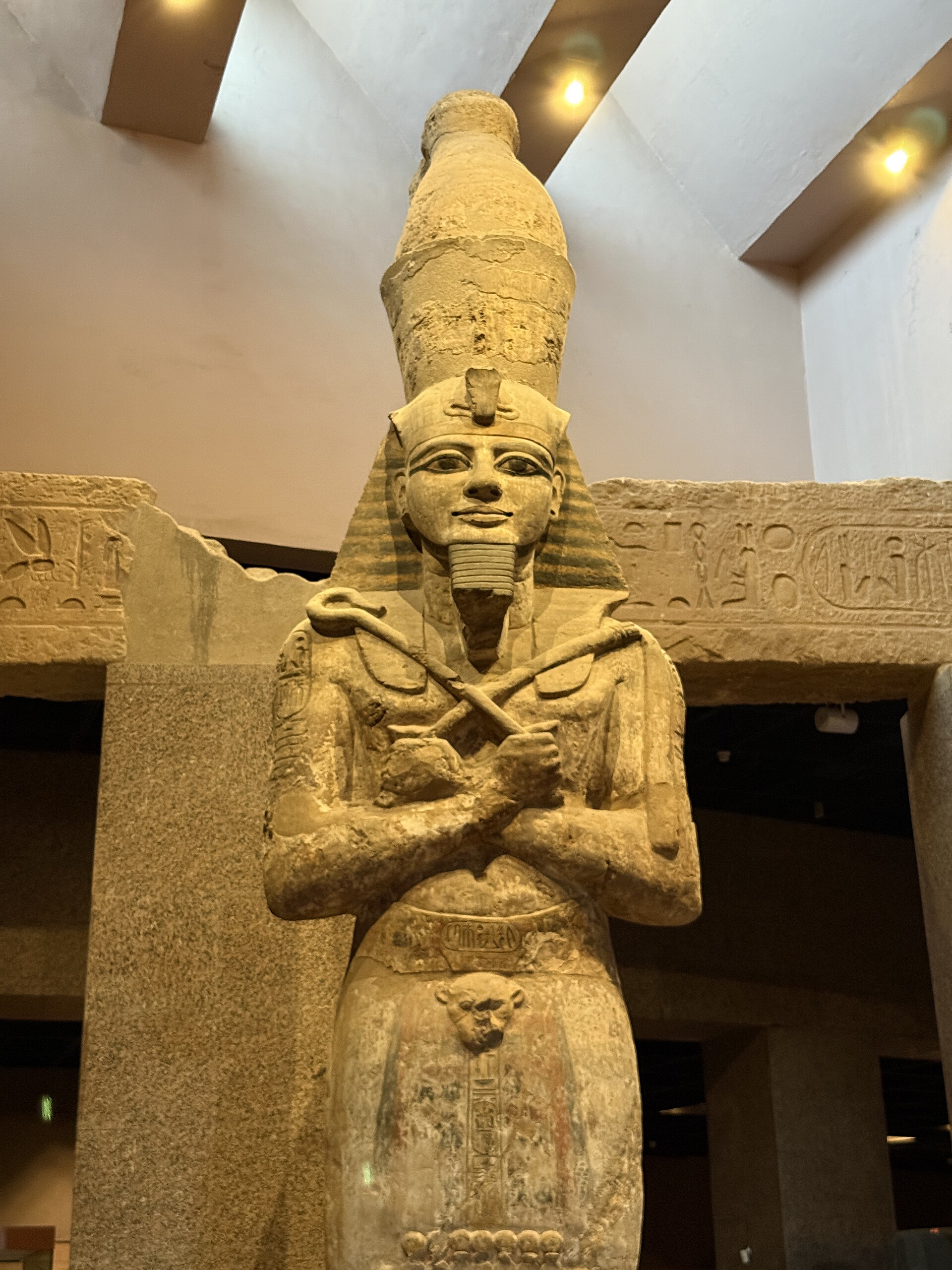 A colossal stone statue of a pharaoh with crossed arms in the museum's main exhibition hall
