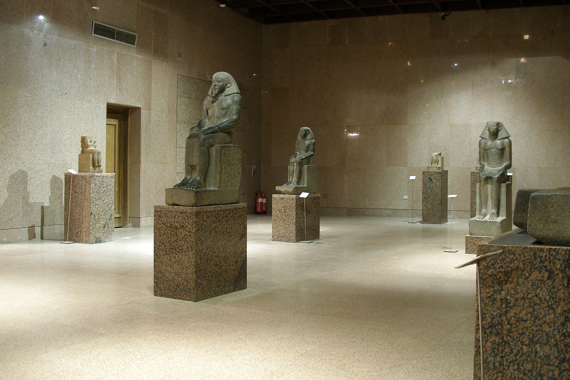 A gallery of ancient Egyptian and Nubian statues displayed on individual plinths
