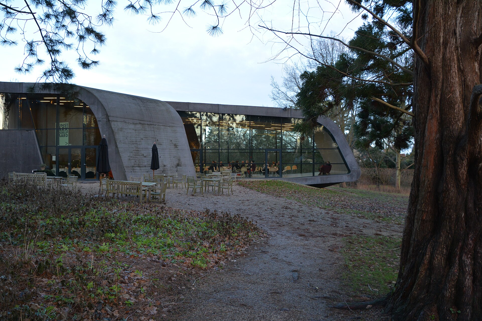 A dining room inside the Zaha Hadid extension, with the extension's black lava-concrete walls and a run of glazing along one side