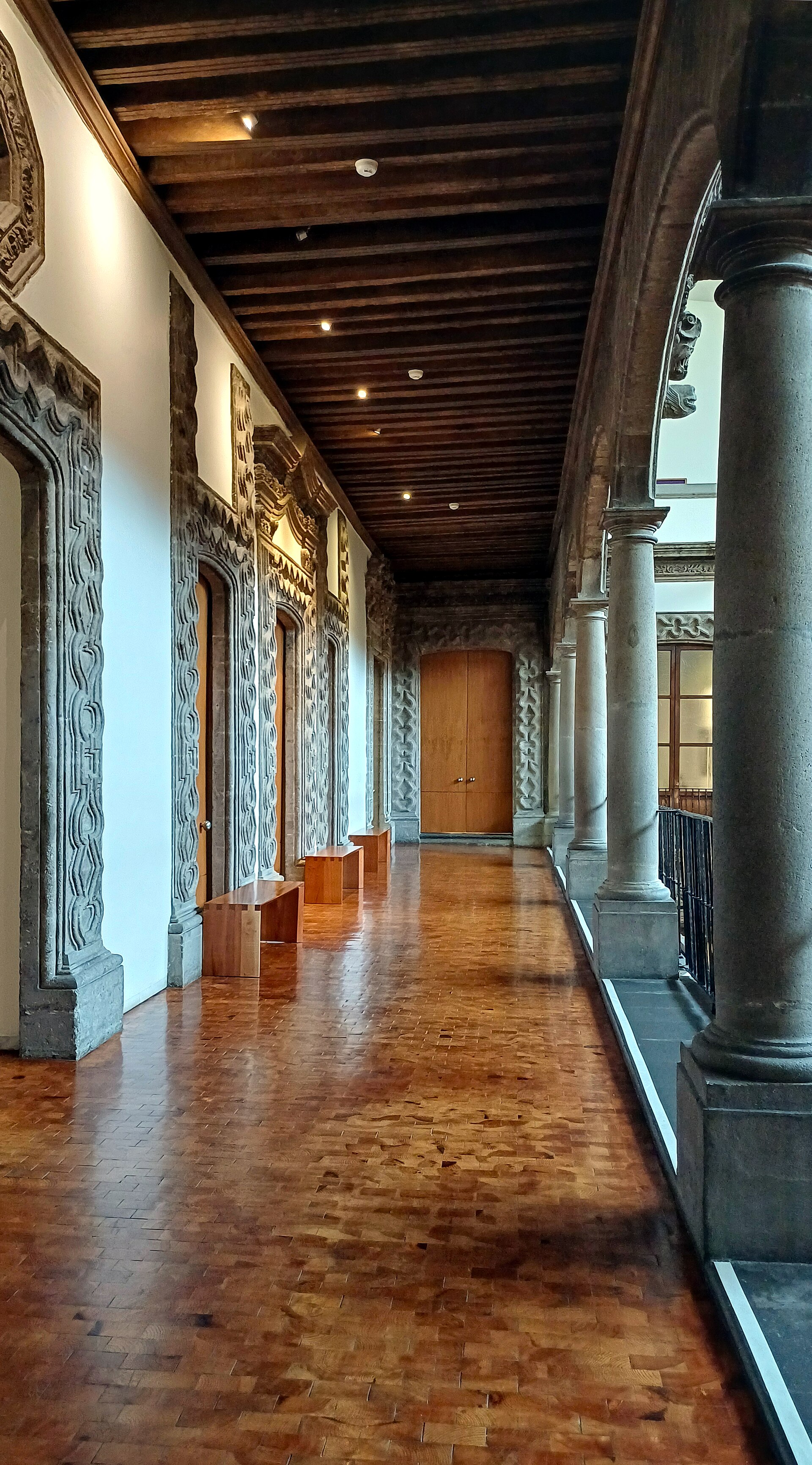 The carved stone and wood-beamed upper corridor overlooking the courtyard