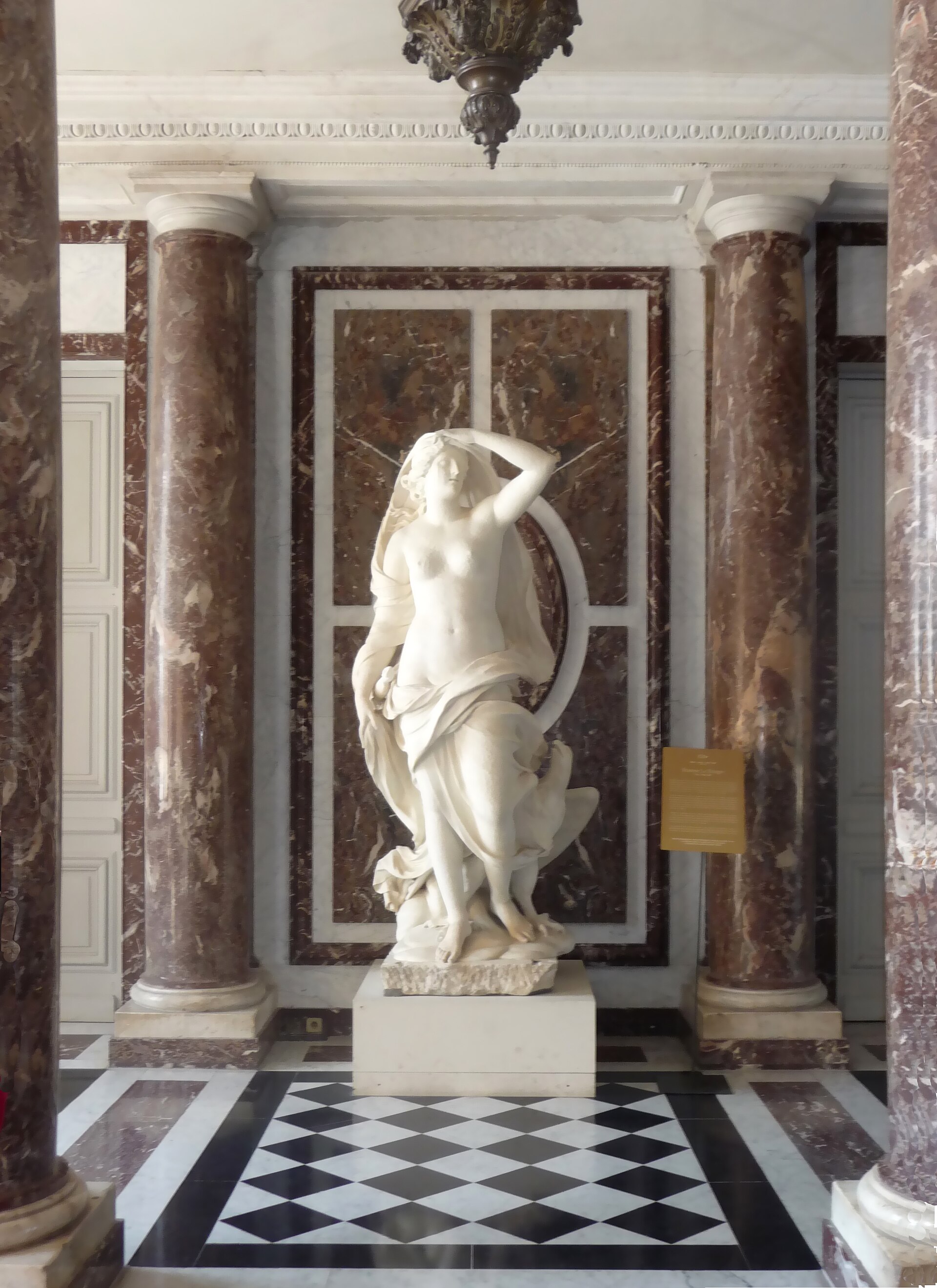 A marble-columned salon inside the Palace, hung with paintings and furnished, part of the State Apartments