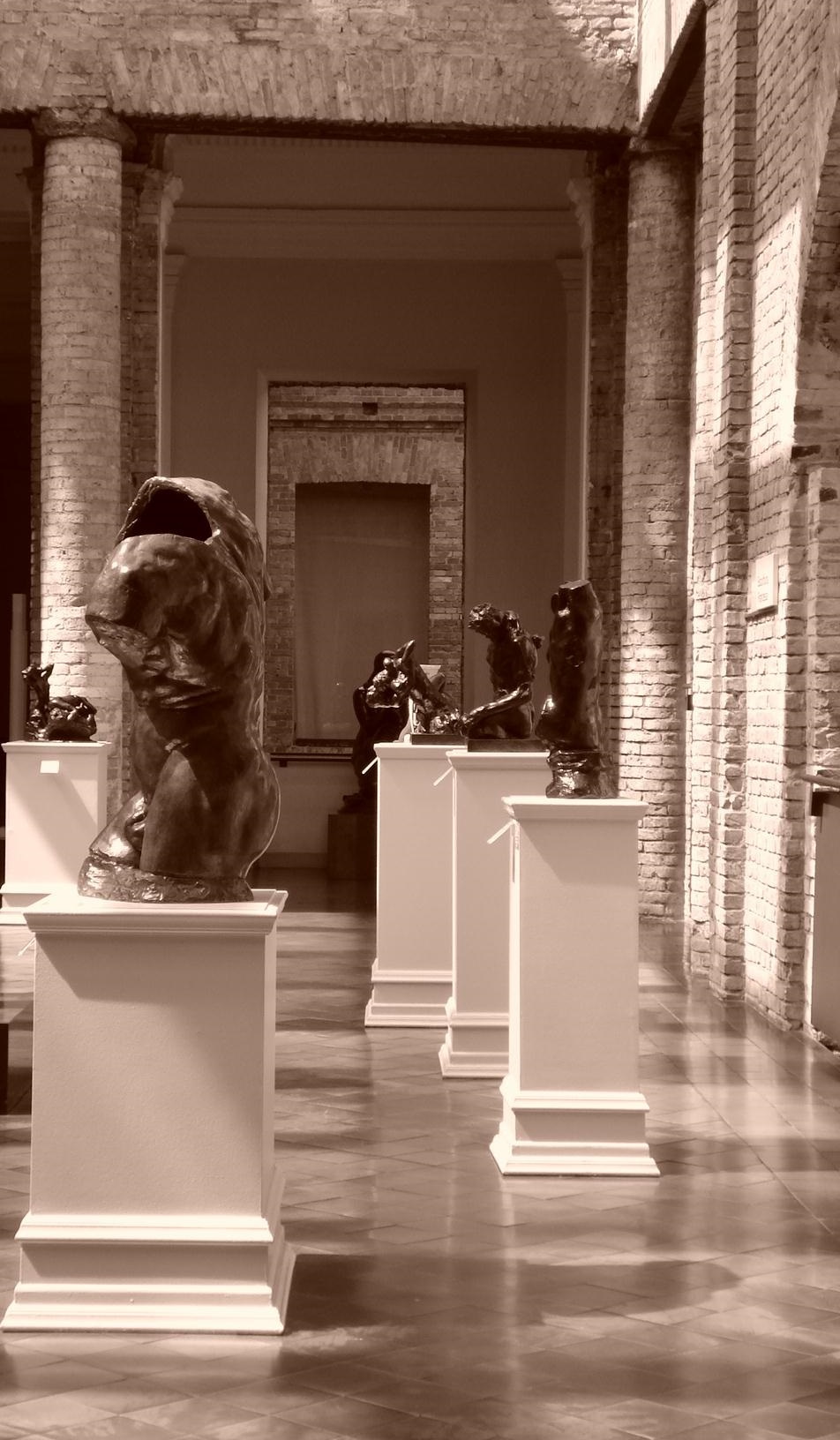 Bronze sculptures on plinths in a colonnaded gallery at the Pinacoteca do Estado