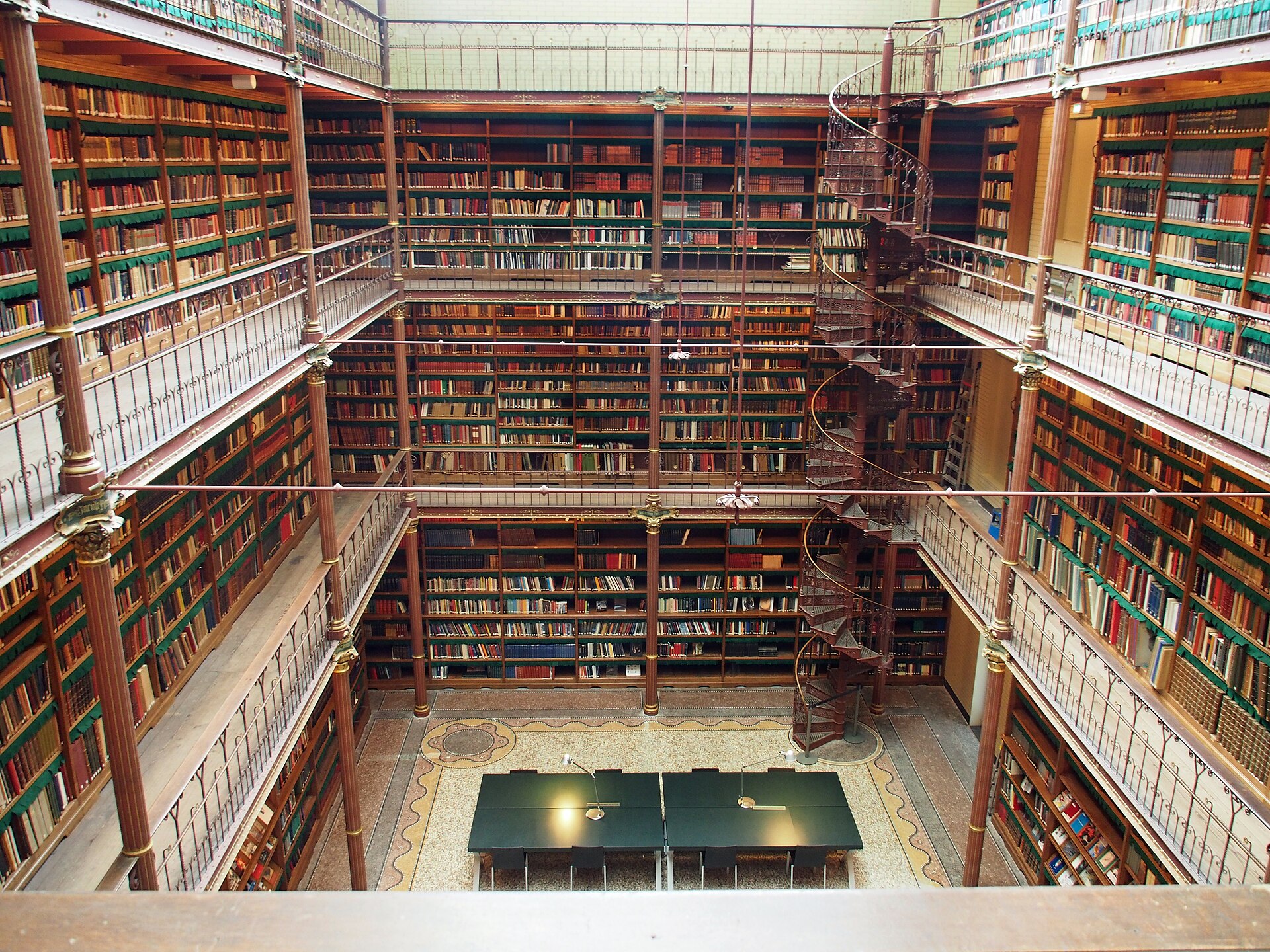 The library hall from above, cast-iron galleries of books on three levels around a spiral stair