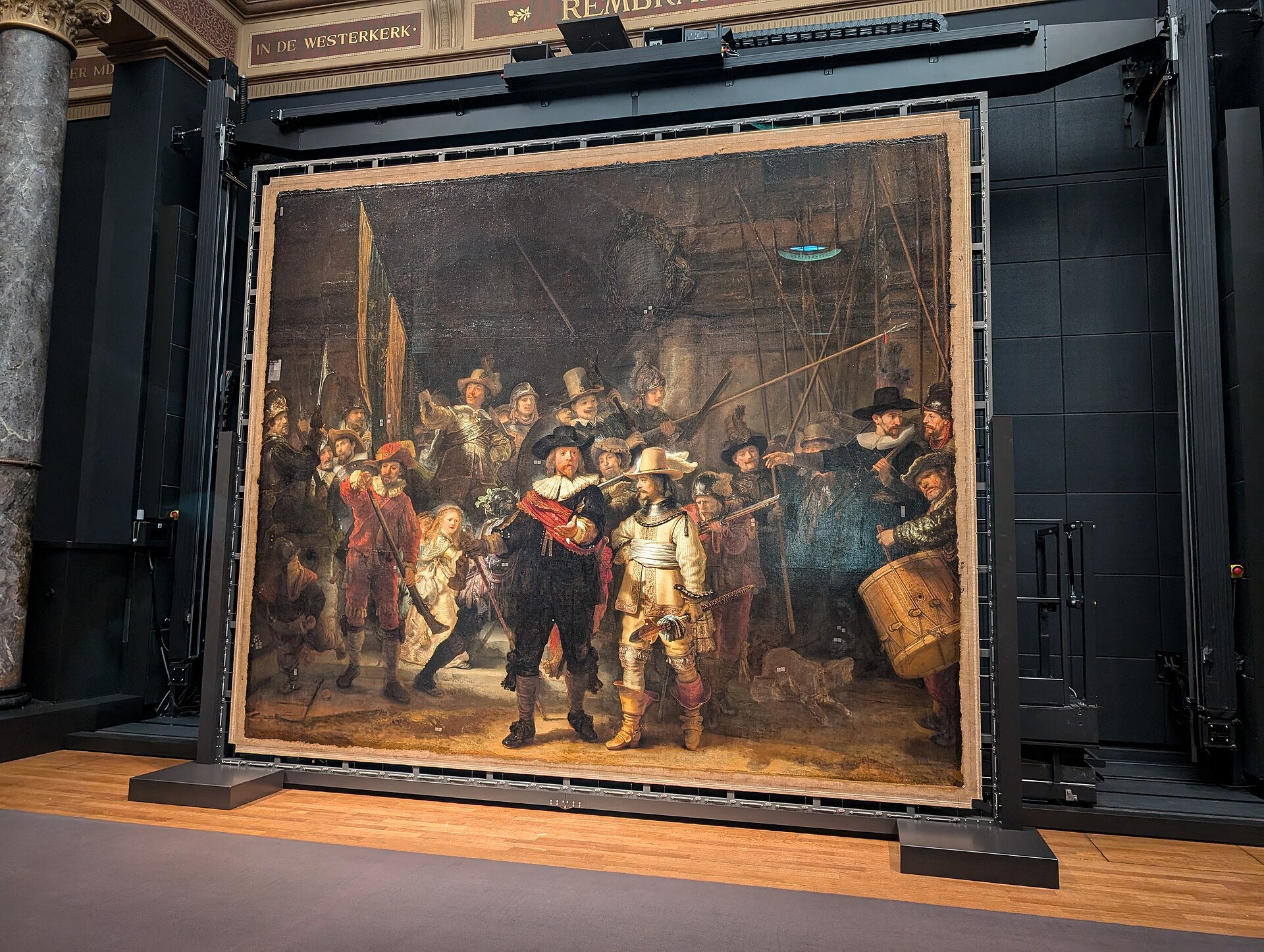 The Night Watch off the wall in a steel frame with a scanning gantry above it, on public view during the treatment