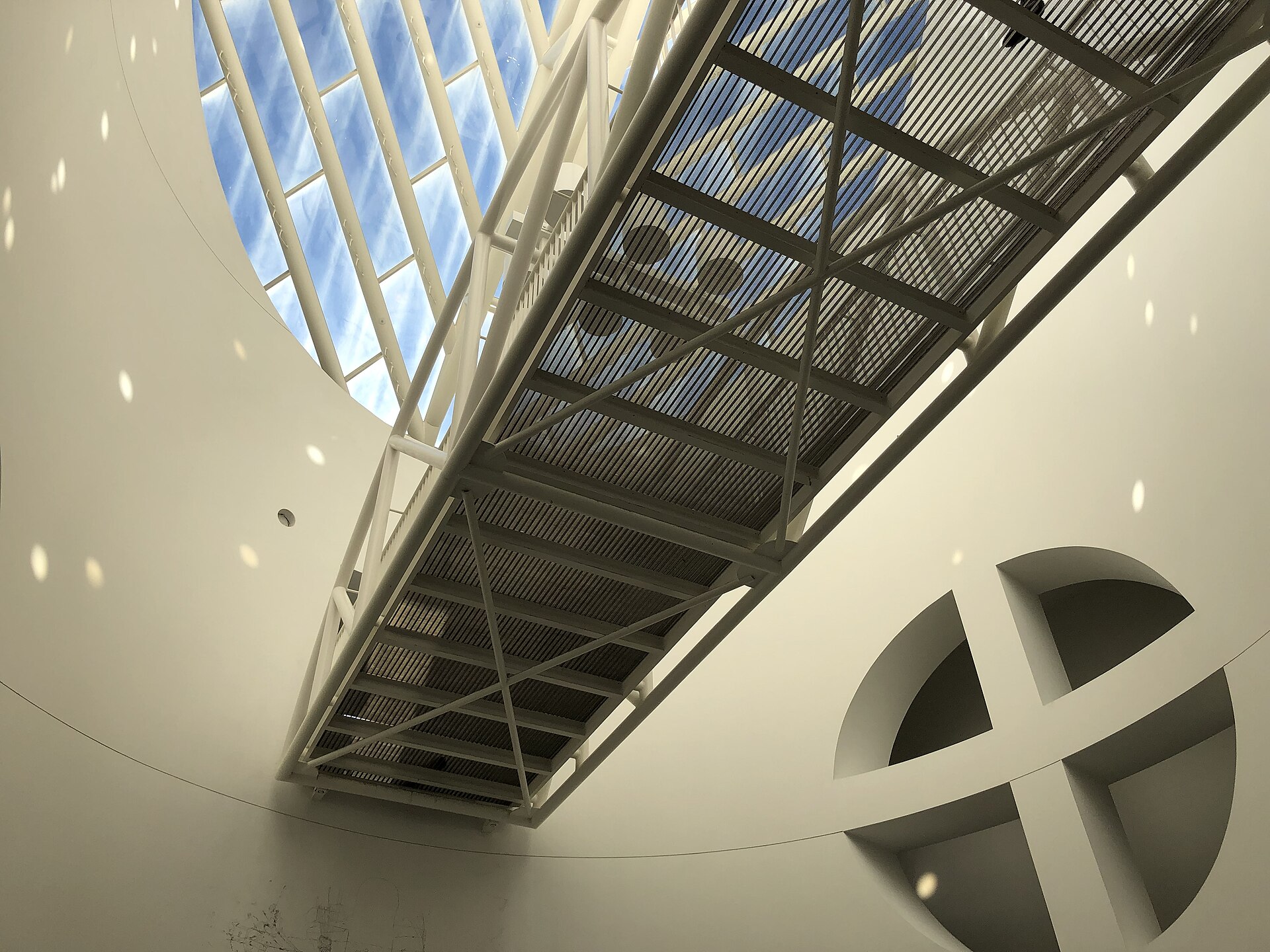 A steel and glass skybridge crossing over the Botta oculus, seen looking up from below