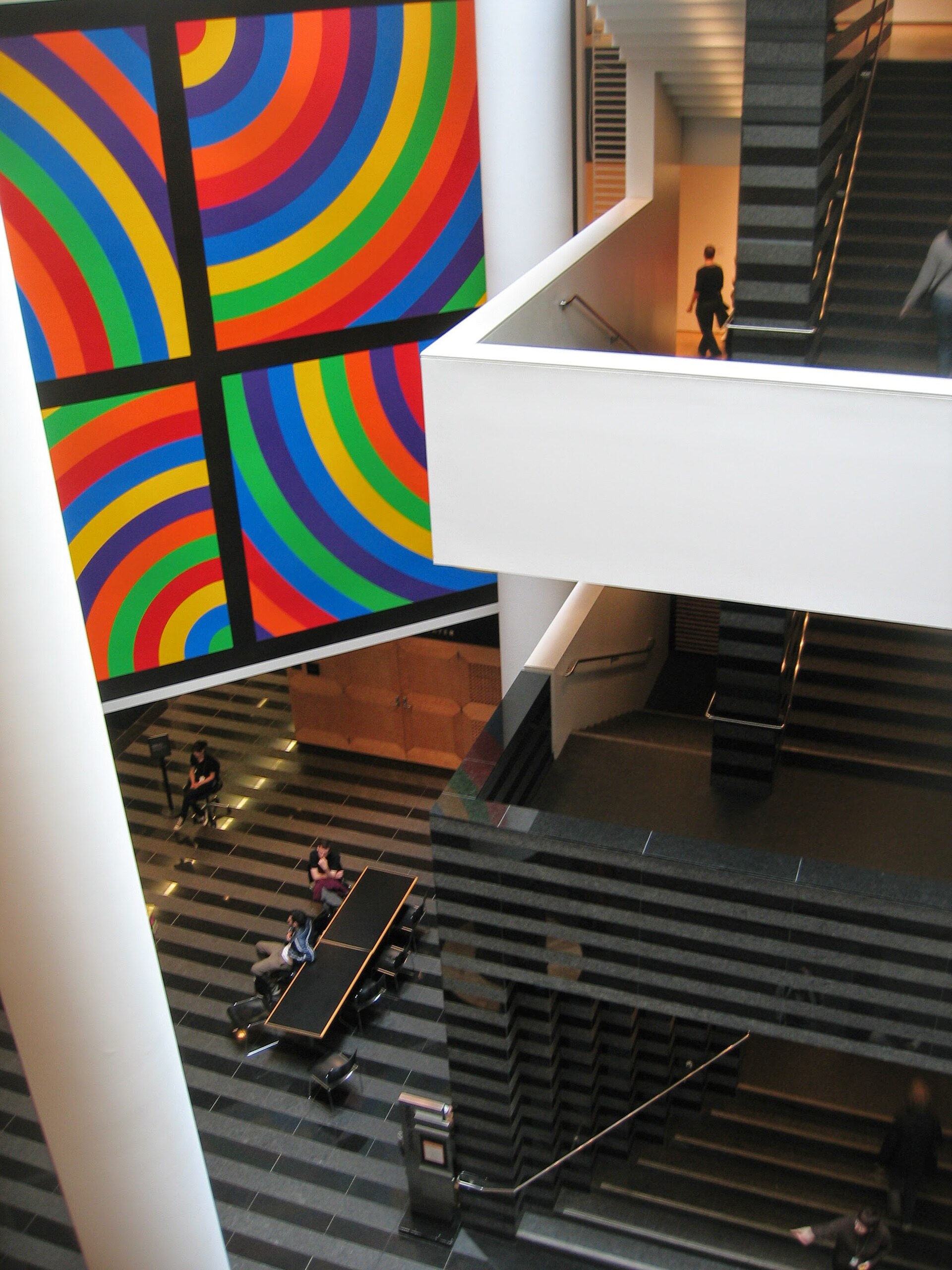 The black and white striped grand stair inside the museum's main atrium, with a large striped painting on the wall above