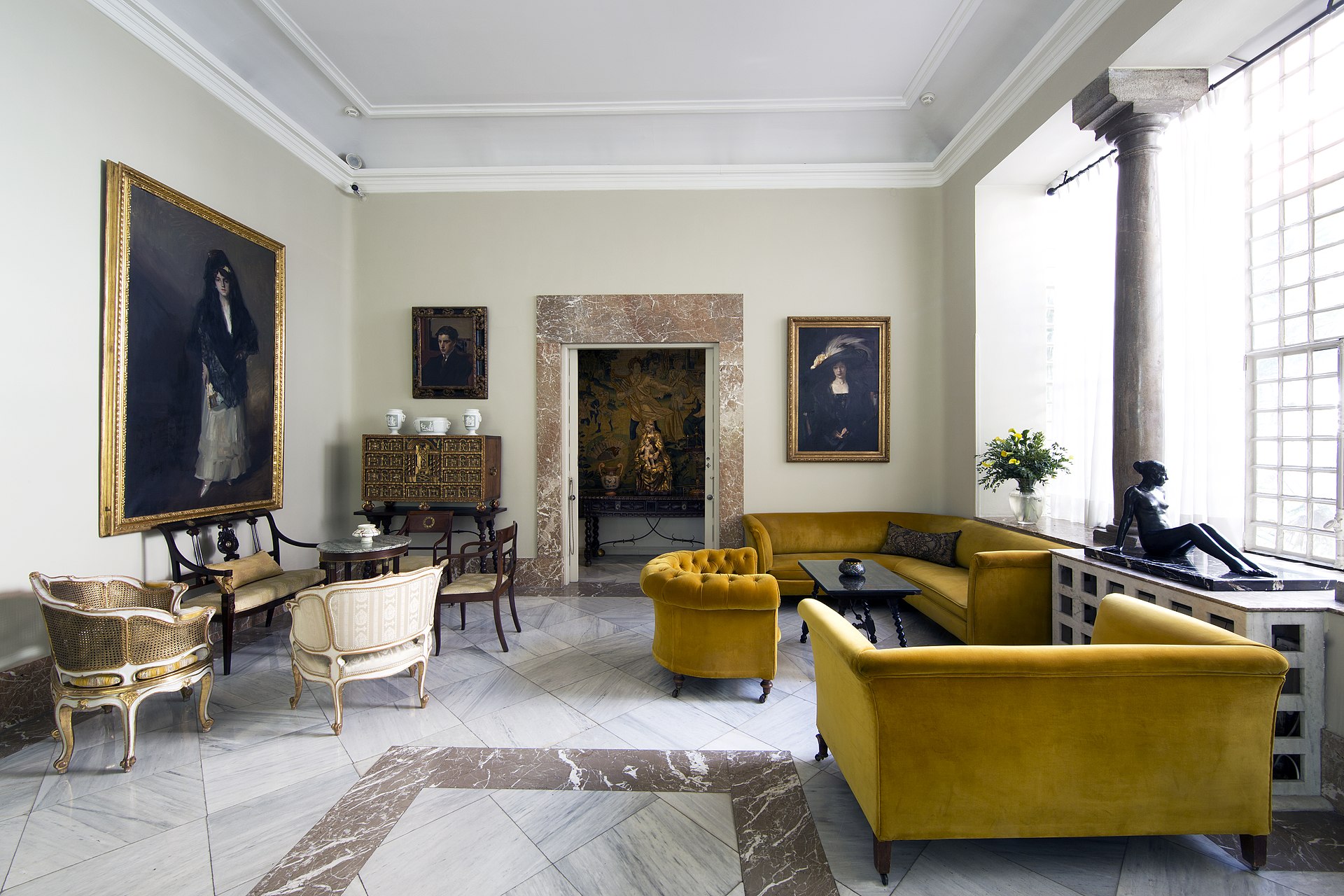 The Salon, with family portraits in gilt frames, gold velvet sofas and a marble floor