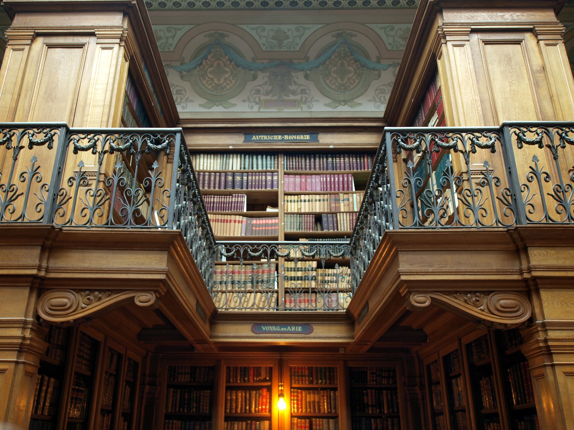 Two-storey library with iron balcony railings and shelves of leather-bound books at Teylers Museum