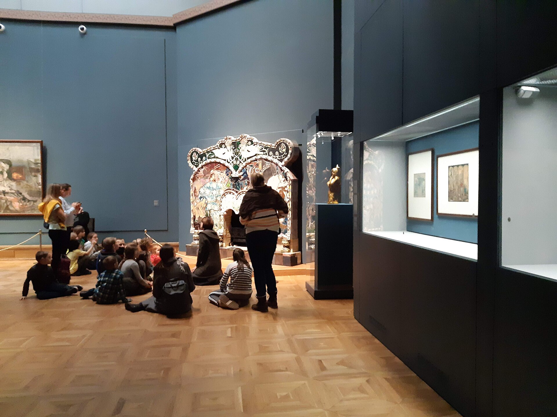 The Vrubel hall, with his majolica fireplace and a school group seated on the floor for a tour