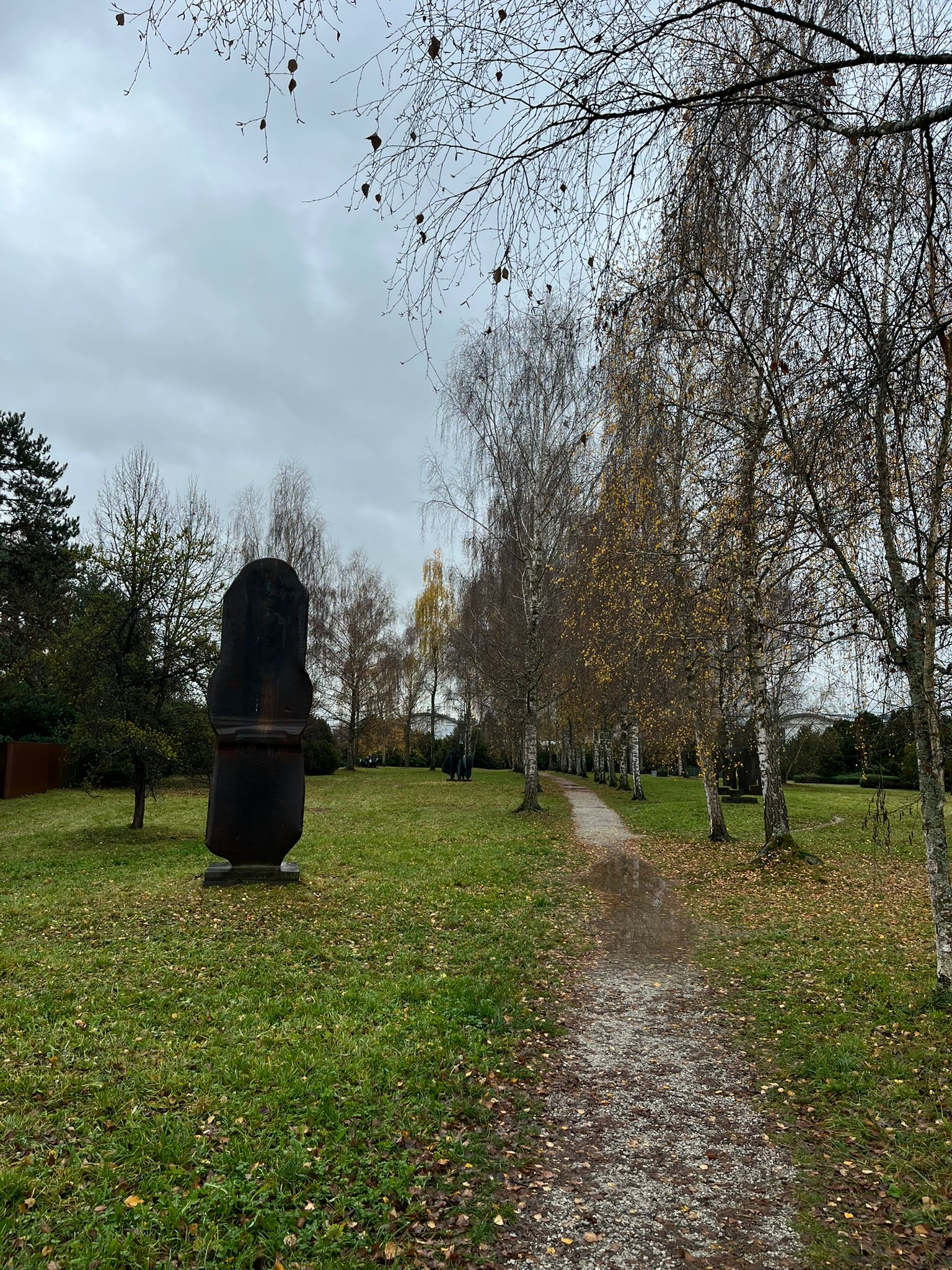 A path through the outdoor sculpture park at Zentrum Paul Klee, with a bronze sculpture beside the path